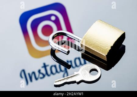 Un verrou de sécurité ouvert et une clé sur l'arrière-plan du logo du réseau social Instagram dans le miroir. Banque D'Images