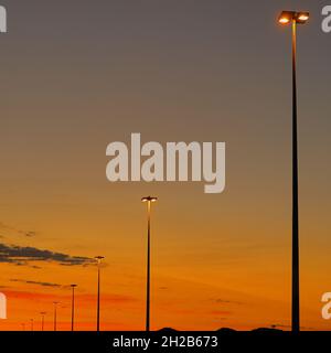 Lumières de rue devant le ciel du coucher de soleil dans les couleurs du feu, rouge, orange, jaune.Technologie, électricité, infrastructure routière, coucher de soleil, concept de fond Banque D'Images