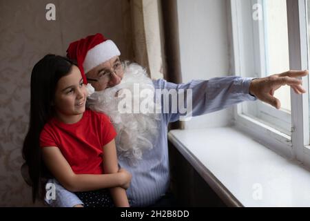 Photo d'un homme âgé portant un chapeau de père Noël tout en jouant avec ses petits-enfants Banque D'Images