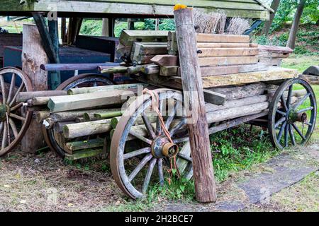 Ancien wagon de ferme en bois abandonné avec roues en bois, chargé de poutres et poteaux en bois Banque D'Images