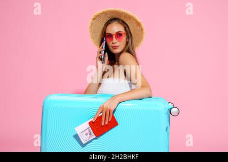 La fille voyageur tient le passeport, les billets, l'argent avec des valises appelle le taxi à l'aéroport.Concept de voyage Banque D'Images