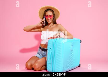 Une femme heureuse tient un passeport, des billets, de l'argent avec une valise appelle un taxi pour l'aéroport.Concept de voyage Banque D'Images