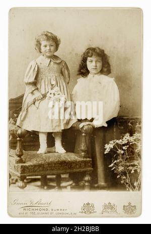 Original victorien carte de cabinet des années 1890 de deux jeunes enfants victoriens, détail fumé sur la robe du plus jeune enfant, de l'atelier de Gunn & Stuart, Richmond, Surrey, Royaume-Uni vers 1896 ou 1897. Banque D'Images