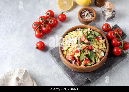 Salade avec bulgur, tomates, concombres et persil.Plat de taboulé.Cuisine orientale.Copier l'espace. Banque D'Images