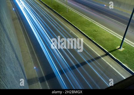 Sentiers légers sur la route du passage souterrain la nuit.Photo d'arrière-plan de la circulation ou de l'autoroute.Deux voies de route et des sentiers légers de voitures. Banque D'Images