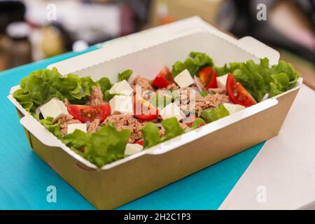 Salade de légumes au fromage de thon et feta avec tomates cerises conditionnées dans une assiette de corton pour livraison. Banque D'Images