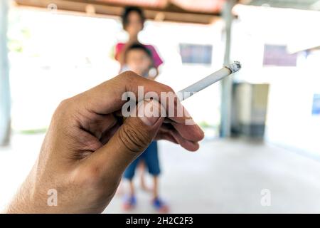 Focus sur la cigarette à la main avec le fond de burroux de choldrens;concept pour la Journée mondiale sans tabac. Banque D'Images