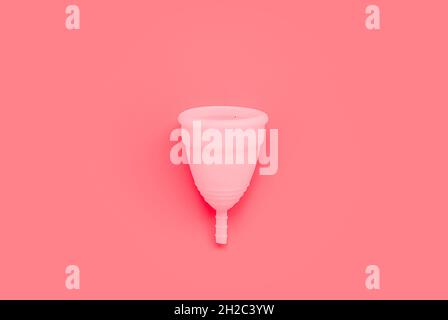 Coupe menstruelle rose sur fond de couleur, produits d'hygiène intime féminins, vue du dessus Banque D'Images