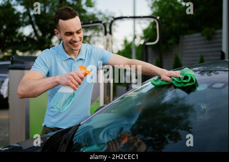 Homme utilisant un nettoyant pour vitres et un chiffon, laver à la main à l'auto Banque D'Images