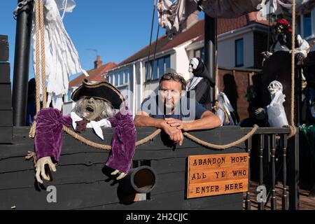 Andrew Carvel avec le bateau pirate géant « Elizabeth Dane » qu'il a construit en utilisant du bois de ferraille dans le jardin de sa maison à Tamworth, Staffordshire.Le navire mesure neuf mètres de long et est orné d'un drapeau pirate, de squelettes et de voiles sanglées, et il a fallu quelques semaines à M. Carvel pour le construire.Date de la photo: Jeudi 21 octobre 2021. Banque D'Images