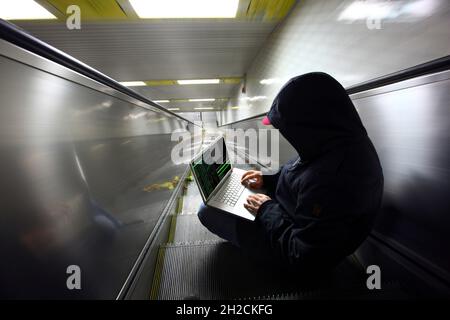 Image symbolique piratage informatique, cybercriminalité, cyberattaque, pirate avec ordinateur portable dans une station de métro, Banque D'Images