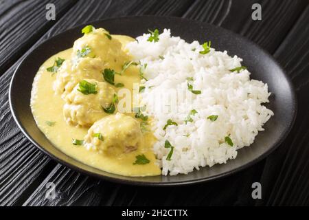 Recette traditionnelle de boulettes de viande danoises à Curry Boller i Karry avec garniture de riz dans la plaque sur la table. Horizontale Banque D'Images