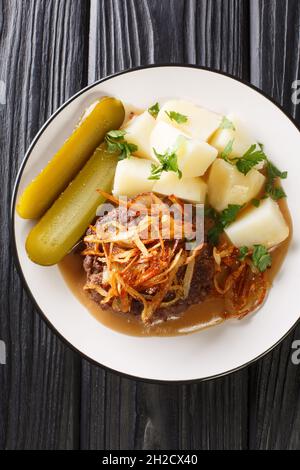 Patties de bœuf danoises hakkebof à base de viande hachée de bœuf, servi avec des pommes de terre, des oignons et de la sauce brune, à proximité de l'assiette sur la table.Vue verticale du dessus f Banque D'Images