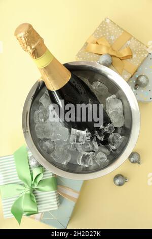 Composition du nouvel an avec champagne et cadeaux sur fond jaune clair. Banque D'Images