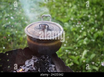 Vieille poêle sur la cuisinière à l'extérieur en processus de préparation de thé à base de plantes. Banque D'Images