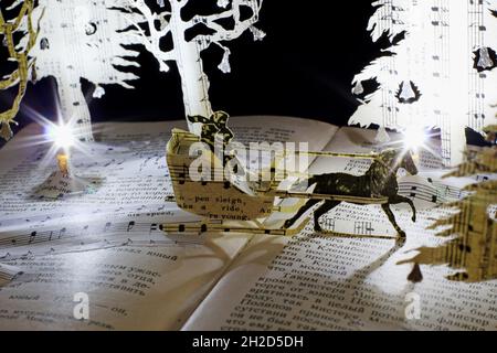Interprétation papier faite à la main de Jingle Bells comme une scène de sculpture de livre.Un traîneau traverse un merveilleux pays hivernal magique. Banque D'Images
