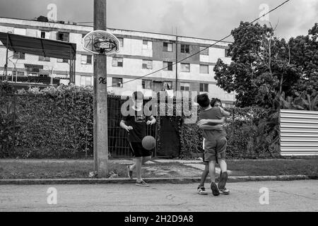 LA HAVANE, CUBA - 22 septembre 2021 : une photo en niveaux de gris d'enfants jouant au basket-ball dans la rue, portant des masques médicaux de la covid19 à la Havane, Cuba Banque D'Images