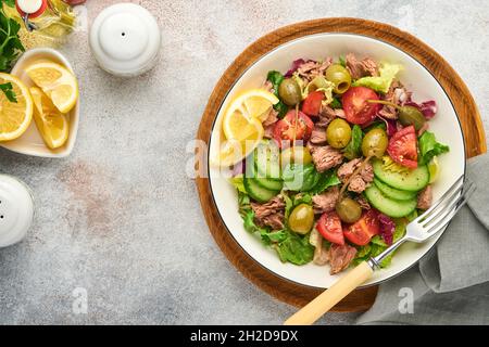 Salade de thon avec légumes frais, olives, câpres et citron servie dans un bol sur fond gris clair. Vue de dessus avec espace de copie. Banque D'Images