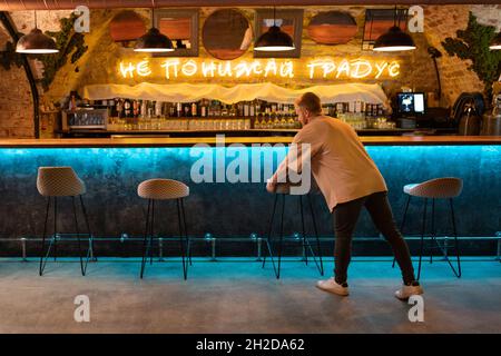 Homme dans des vêtements décontractés arranger des tabourets près du comptoir tout en préparant le club pour l'ouverture Banque D'Images