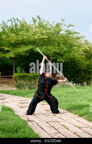 Une femme pratique le kung fu avec un bâton Banque D'Images