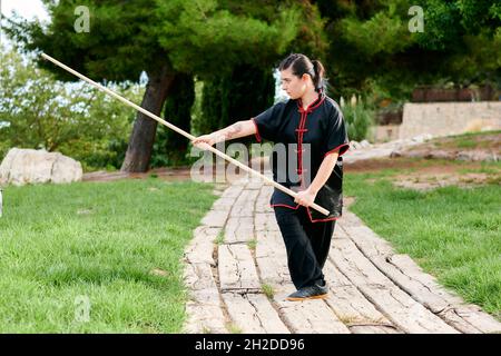 Une femme pratique le kung fu avec un bâton Banque D'Images