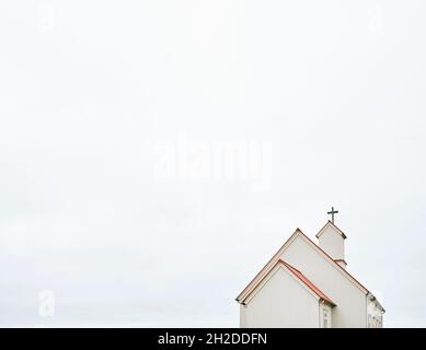 Façade de l'église catholique avec croix sur cheminée sous ciel clair en journée en Islande Banque D'Images