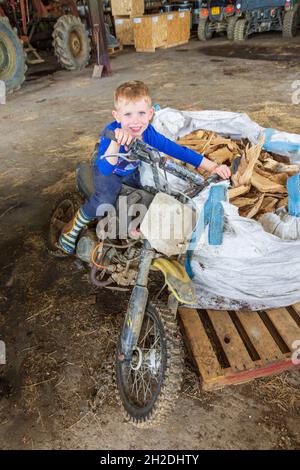 Garçon de cinq ans assis sur une vieille moto, Devon, Angleterre, Royaume-Uni. Banque D'Images