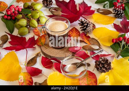 Tasse à café sur fond de feuilles d'automne jaunes et rouges avec la main d'une femme Banque D'Images