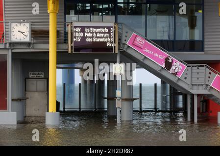 21 octobre 2021, Schleswig-Holstein, Dagebüll: L'eau se trouve sur le quai du terminal de ferry à Dagebüll, au fur et à mesure que le niveau de la mer du Nord monte.Un panneau d'affichage annonce des retards dans les ferries vers les îles en raison du temps orageux.Le bas 'Ignatz' se déplace au-dessus du Schleswig-Holstein jeudi.Photo: Bodo Marks/dpa Banque D'Images