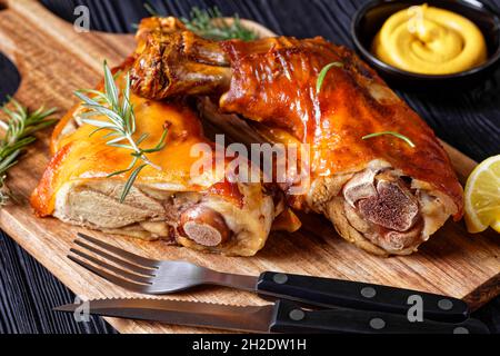 gros plan de tiges de porc grillées croustillantes sur une planche de bois avec romarin, quartiers de citron et moutarde, vue horizontale depuis le dessus Banque D'Images