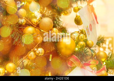 Sapin de Noël décoré de boules dorées et d'une enveloppe avec lettre au Père Noël sur un fond flou et étincelant Banque D'Images