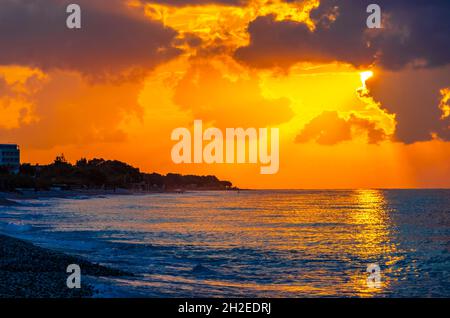 Les couleurs dorées du plus beau coucher de soleil à Ialysos Beach sur l'île de Rhodes en Grèce. Banque D'Images