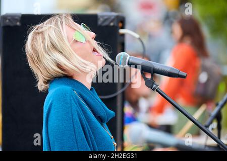 Svetlogorsk, Russie - 08.14.2021 - une chanteuse féminine chante dans le microphone sur scène lors d'un concert de rue, gros plan.Portrait de la chanteuse blonde en su Banque D'Images