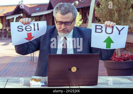 Man recommande de faire une affaire dans acheter ou vendre.Il travaille à la bourse à l'aide d'un ordinateur portable. Banque D'Images