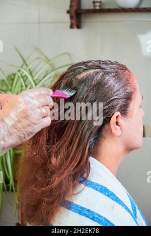 Gros plan d'un mari colorant les cheveux de sa femme à la maison. Banque D'Images