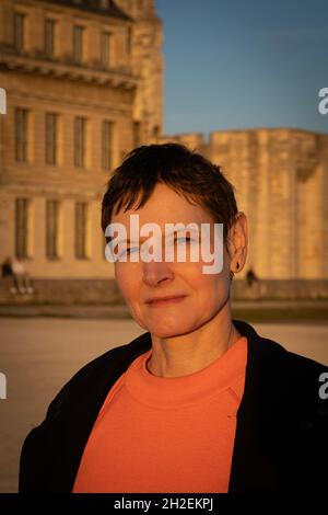 Vincennes, France - 10 16 2021 : château de Vincennes.Portrait d'une femme portant un T-shirt orange et un manteau noir devant la façade du château Banque D'Images