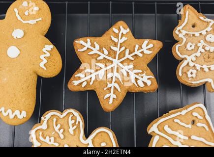 Biscuits de pain d'épice de Noël : bonhomme de neige, sapin, cerf, Père Noël sur plaque à pâtisserie à côté des branches de sapin.Noël cuisine maison Banque D'Images