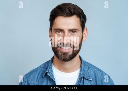 Portrait sourire heureux homme dans des vêtements décontractés isolés sur fond bleu mur Banque D'Images