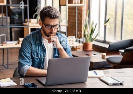 Jeune entrepreneur indépendant adulte utilisant un ordinateur portable dans un espace de travail de collègue Banque D'Images