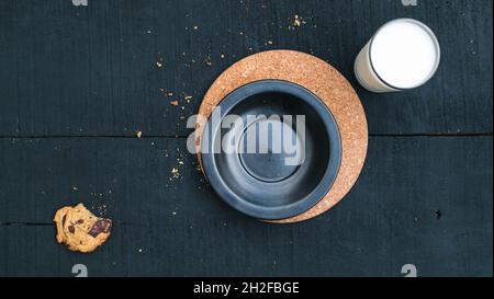 Plat de laque gauche sur le biscuit mordu et le lait sur fond de bois noir Banque D'Images