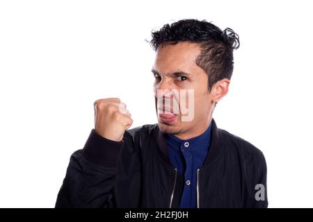 Homme en colère avec le désir de frapper, sur fond blanc.Jeune adulte latino grincheux jeune homme qui claque son poing pour poinçonner. Banque D'Images
