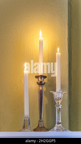 Trois bougies allumées en étain et chandeliers en cristal sur le manteau de cheminée, symbole des vacances, romance, Saint-Valentin et style de vie élégant. Banque D'Images