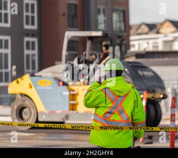 Signal de travaux routiers avec un travailleur debout.Le responsable du contrôle de la circulation surveille l'ordre sur la route urbaine Banque D'Images