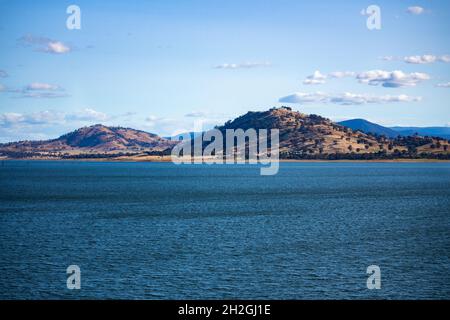 Eaux bleues du barrage de Hume traversant la rivière Murray, en Nouvelle-Galles du Sud, en Australie, le soleil brille sur les collines en arrière-plan Banque D'Images