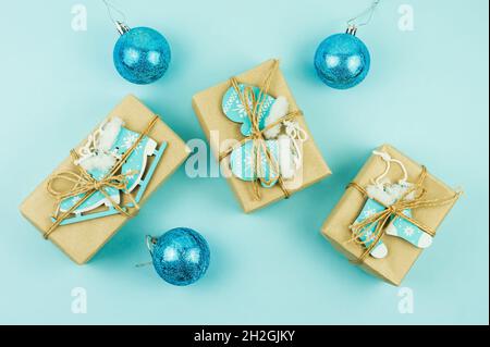 Cadeaux de Noël enveloppés dans du papier artisanal avec différents jouets en bois comme décoration sur fond bleu Banque D'Images