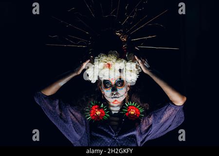 Femme avec crâne mexicain maquillage halloween sur fond sombre.Journée des morts alias Dia de Muertos et fête traditionnelle d'halloween Banque D'Images