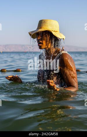 femme noire se baignant dans la mer de galilée srael. eau goutte à goutte et éclabousse comme elle aime le lac tiberius et le soleil. Banque D'Images