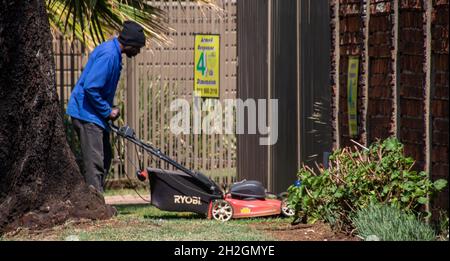 Johannesburg, Afrique du Sud - un homme noir non identifié déplace la pelouse dans une propriété résidentielle Banque D'Images