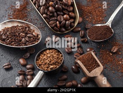 Café moulu et grains de café instantané lyophilisé dans diverses cuillères et cuillères sur fond noir.Macro Banque D'Images