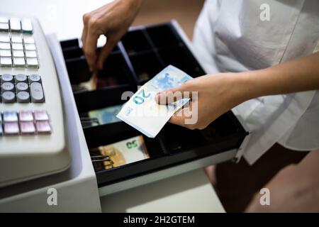 Main du caissier travailler avec la caisse enregistreuse changer la facture d'argent Banque D'Images